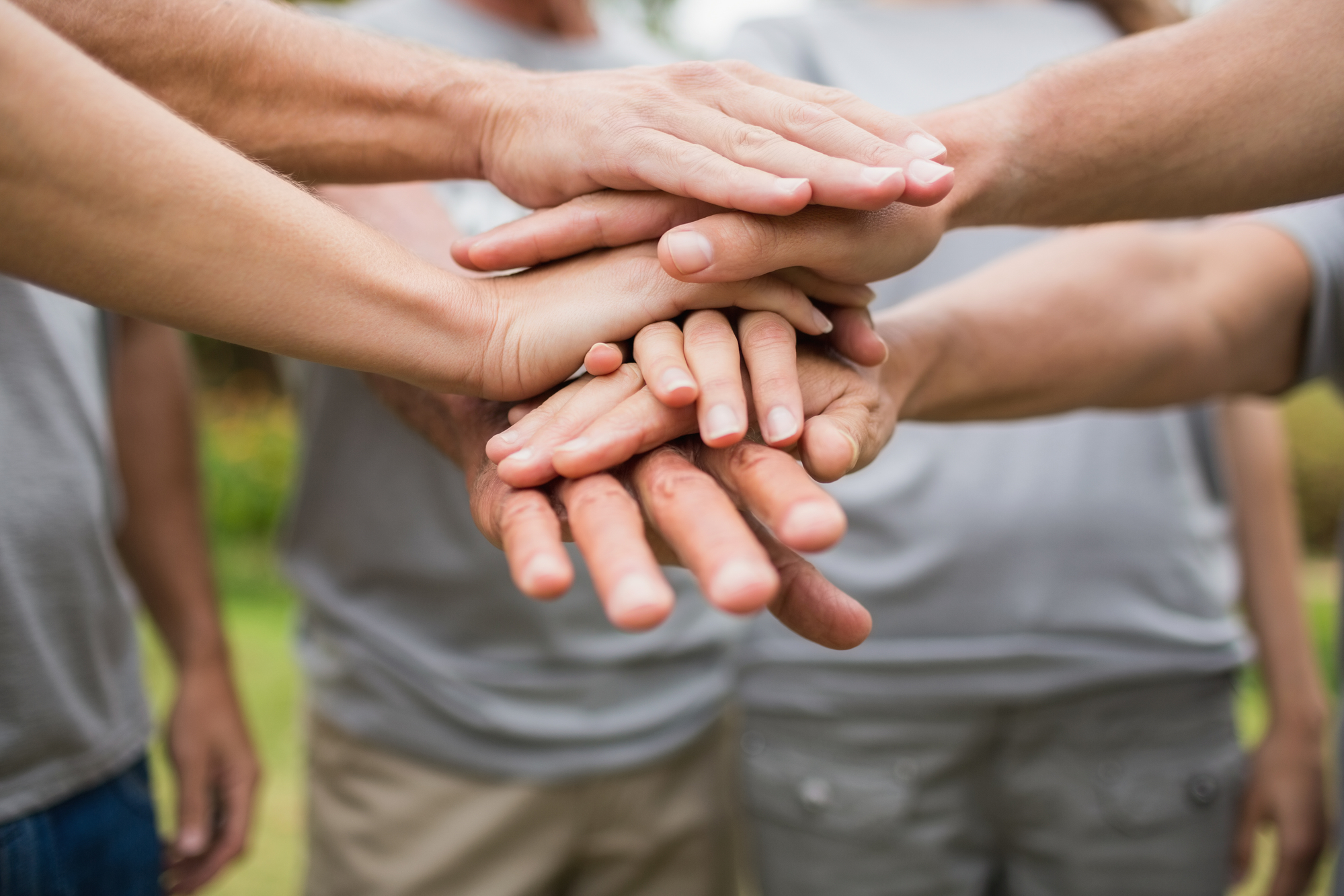 happy volunteer family putting their hands together on a sunny day
